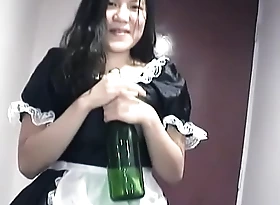 Young Asian girl dressed as a maid indulges herself respecting a bottle be fitting of champagne unaffected by camera for you